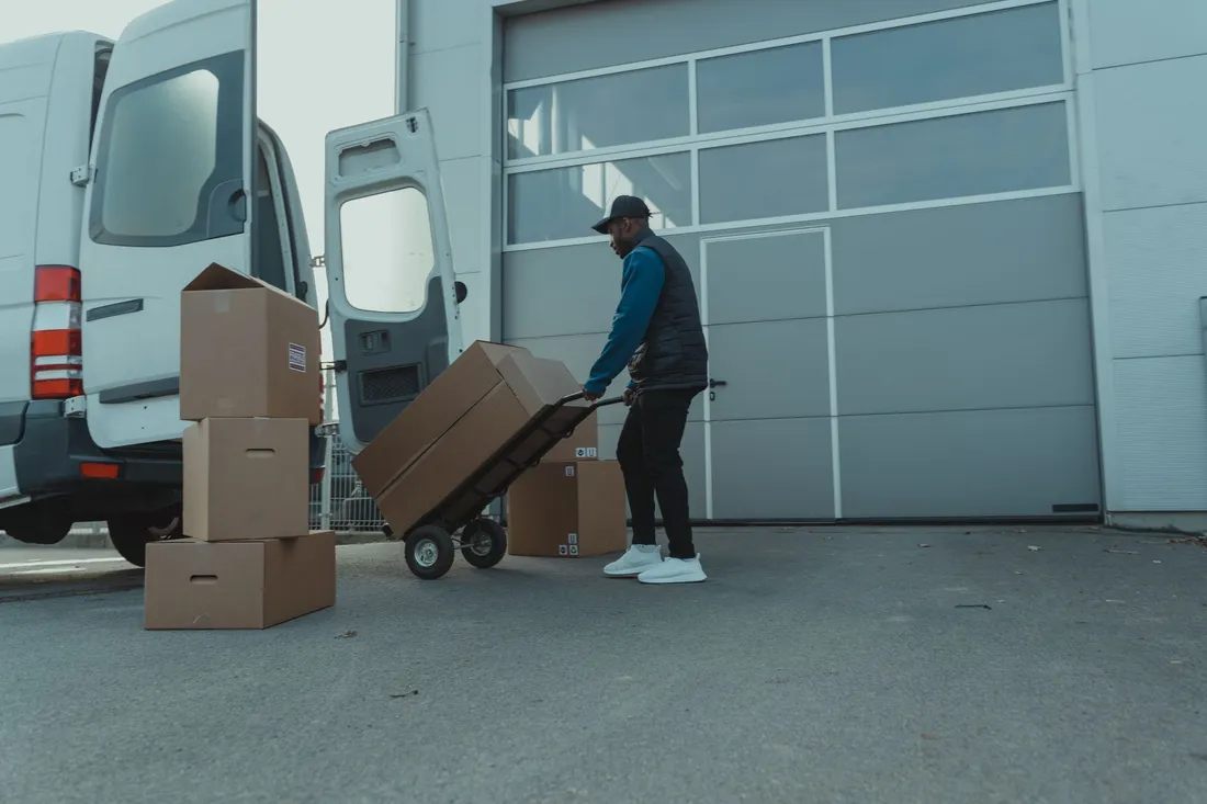 Beladen des Transporters am Hallentor, die Kartons gehen über die Sackkarre an Bord